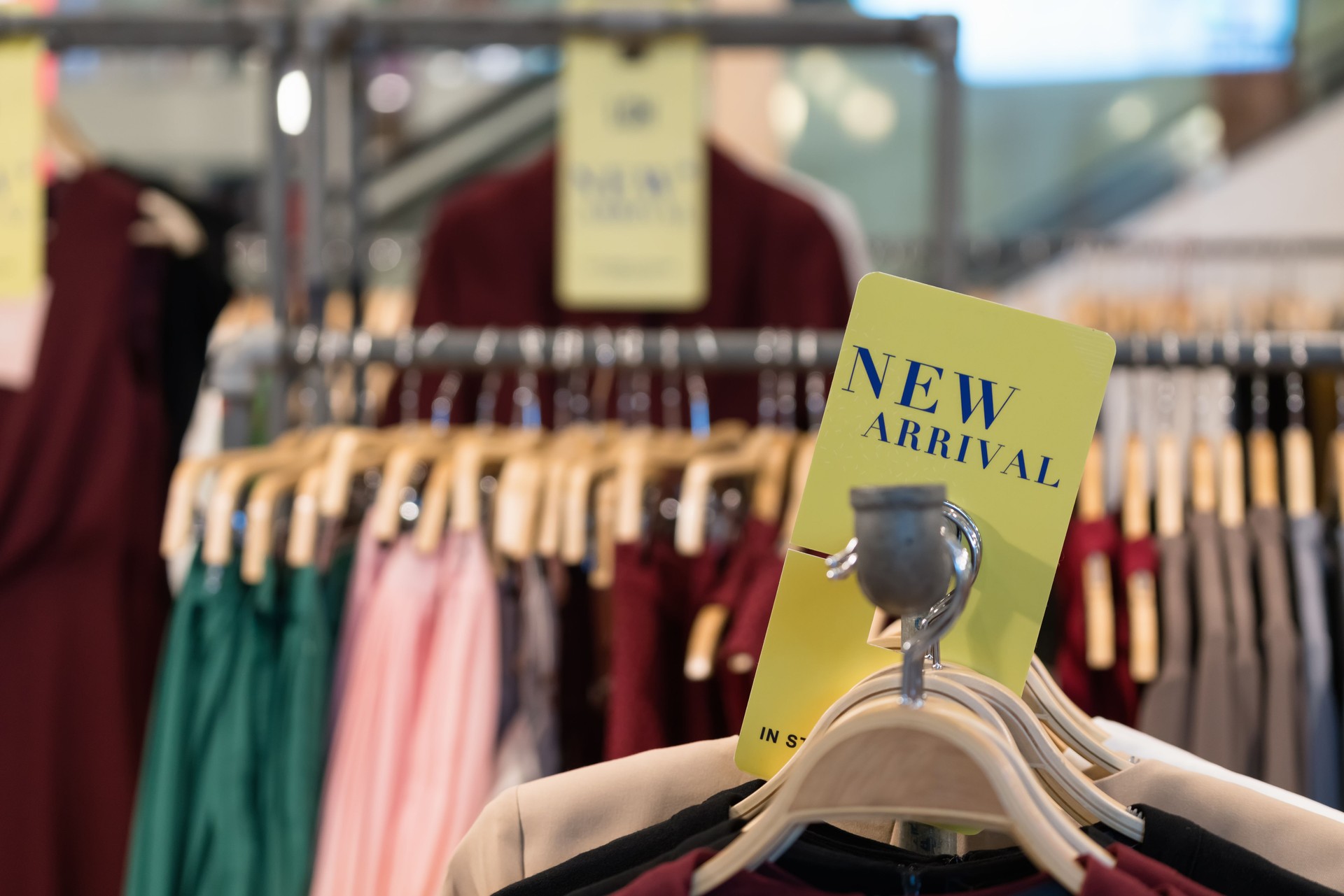 Clothes/shirt on wooden hanger with new arrival fashion tag/sign available in store. Latest cotton shirt for any season collection on rack at flea market/shop. Stall shopping apparel fashion concept.